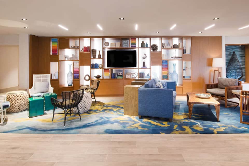 Modern hotel lobby lounge with wooden shelving, blue sofa, and decorative accents