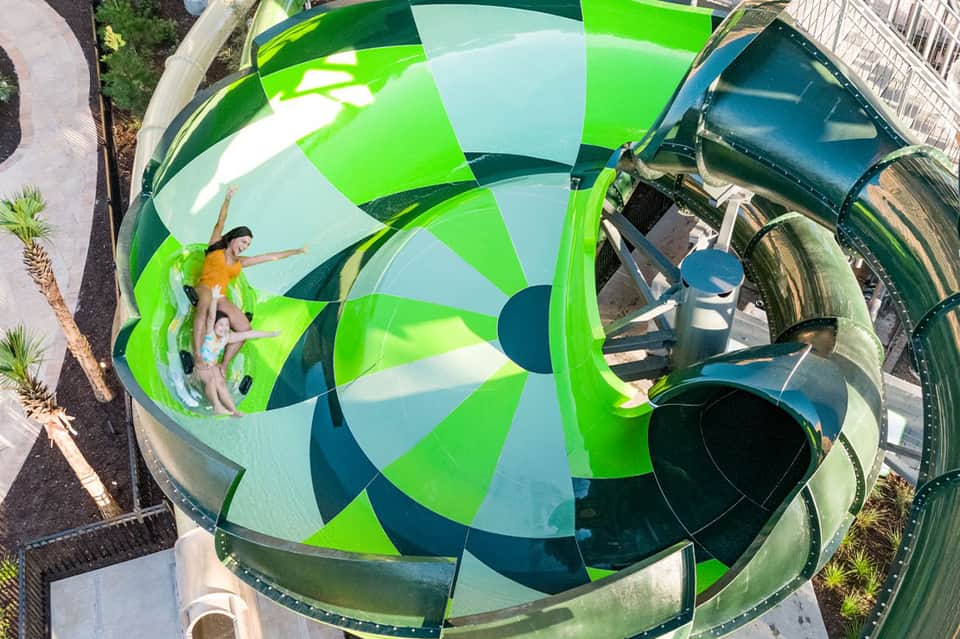 Aerial view of colorful water slide with green and blue sections, children sliding down.