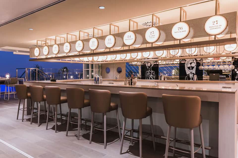 Upscale yacht club bar with numbered plates and ocean sunset backdrop