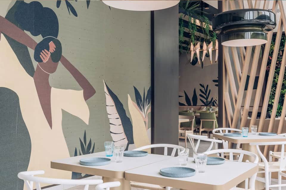 Modern restaurant interior with white tables, botanical wall mural, and contemporary dining setup
