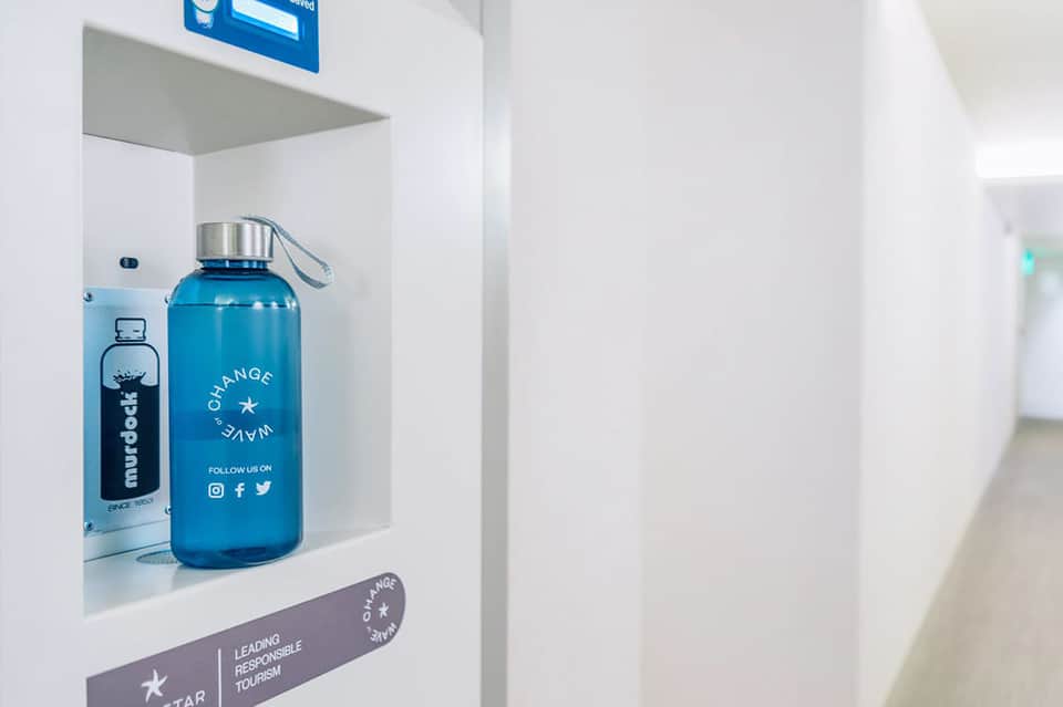 Blue reusable water bottles on white shelf with sustainability messaging