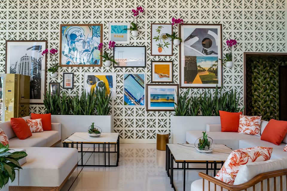 Modern lobby lounge with geometric patterned wallpaper, gallery wall of framed photos, and orange accent pillows