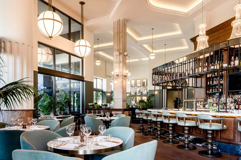 Upscale restaurant interior with elegant lighting, bar seating, blue chairs, and modern design elements