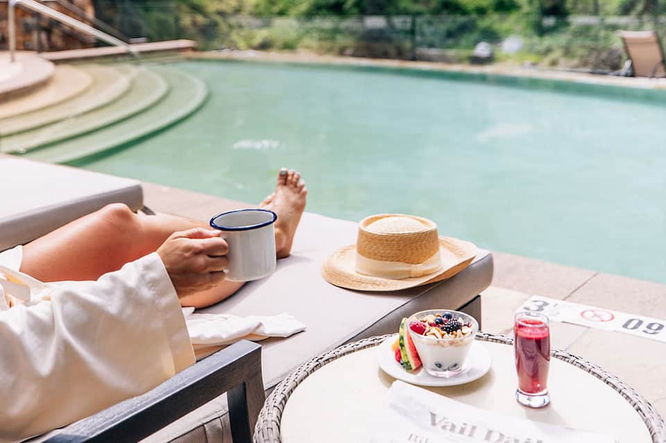 Poolside relaxation with coffee mug, straw hat, and appetizer on white cushioned lounger