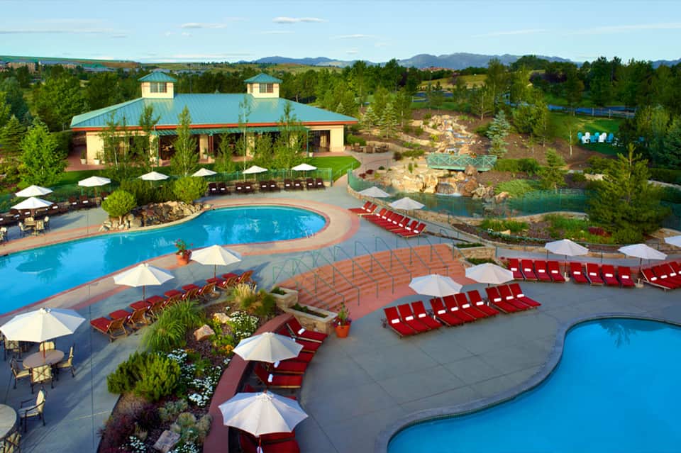 Aerial view of large resort pool with red lounge chairs and mountain backdrop