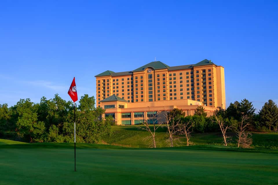 Large orange and green hotel building on hill overlooking golf course with Canadian flag
