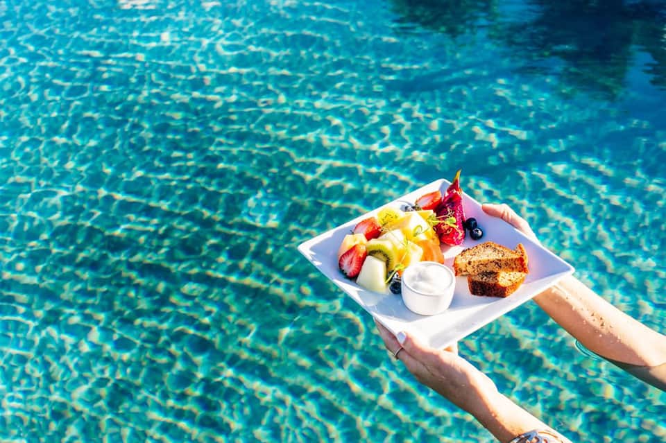 Fruit and pastry plate floating on water surface in resort swimming pool