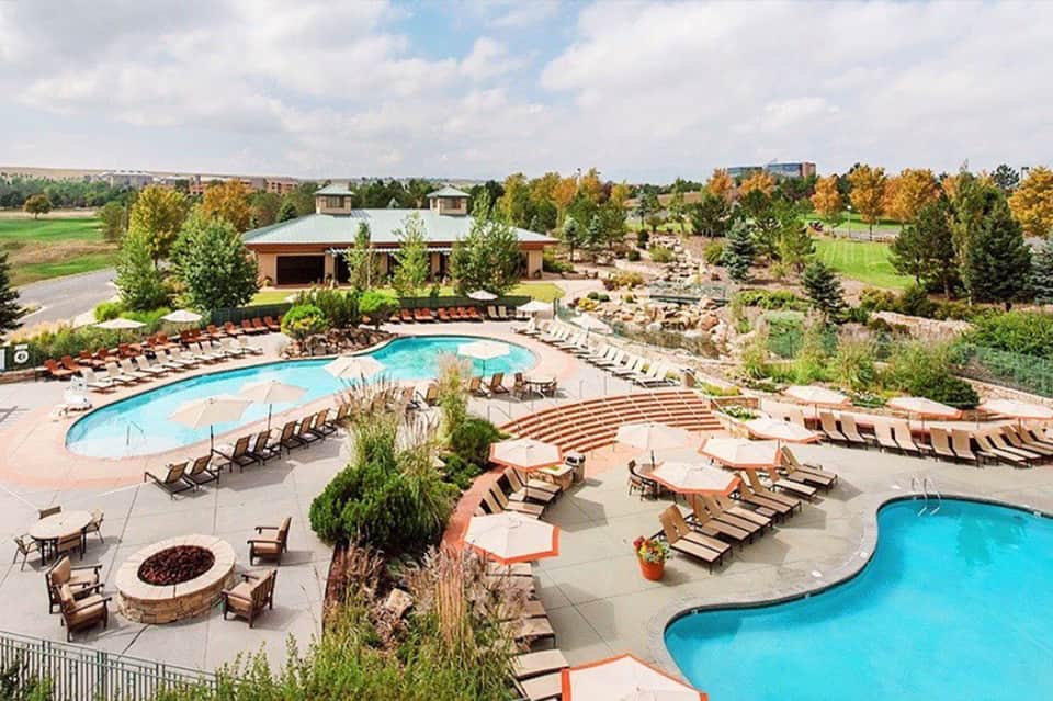 Aerial view of resort complex with curved swimming pools, lounge chairs, and manicured grounds