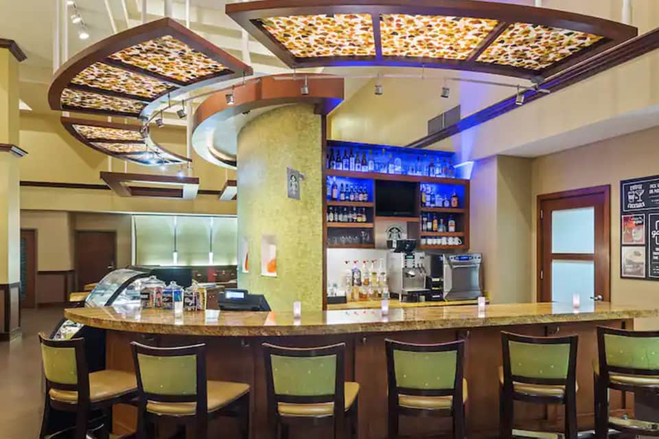 Resort bar with curved design, illuminated ceiling panels, and beverage displays