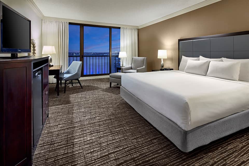 Luxury hotel room with king bed, balcony view, and modern furnishings