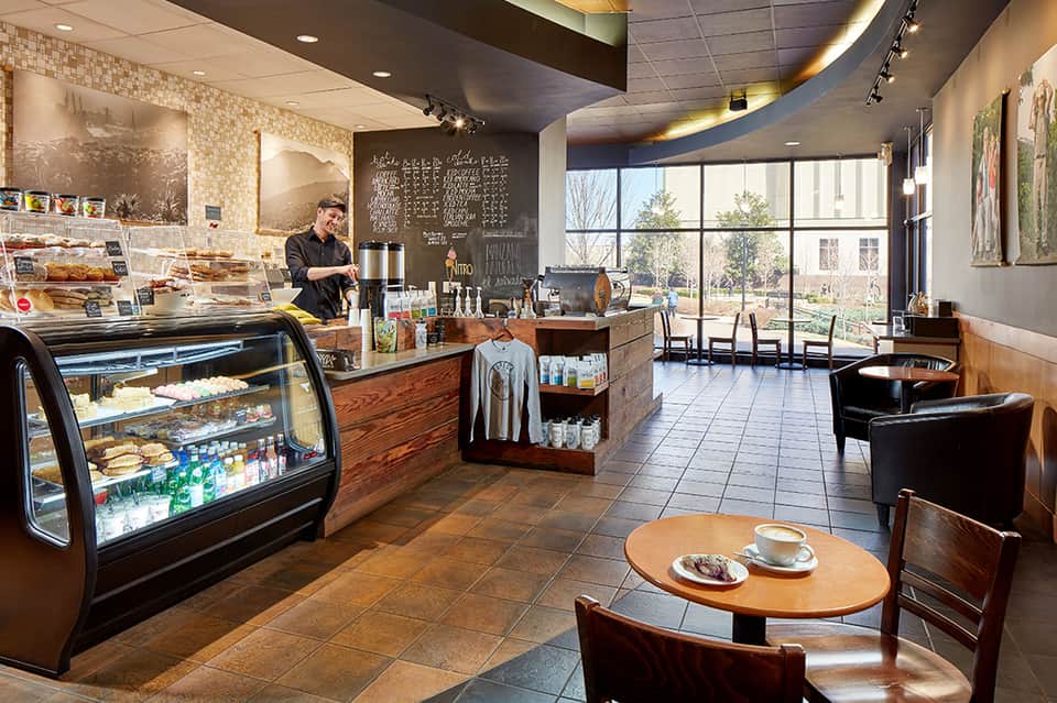 Modern coffee shop interior with pastry display case, counter seating, and large windows