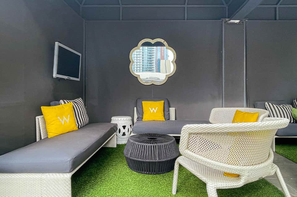 Contemporary lounge area with gray seating, yellow accents, and decorative mirror