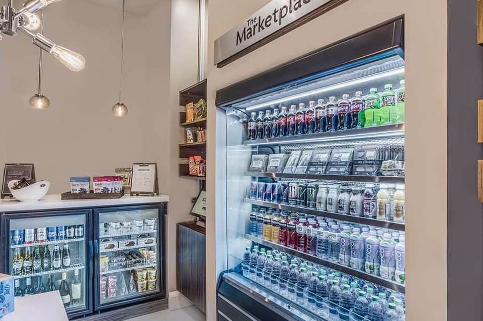 Marketplace refrigerated case displaying beverages, snacks, and packaged goods with pendant lighting