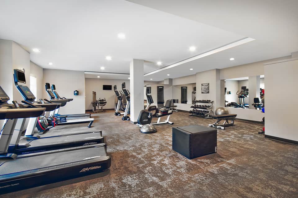 Modern fitness center with treadmills, exercise bikes, weight equipment and mirrors