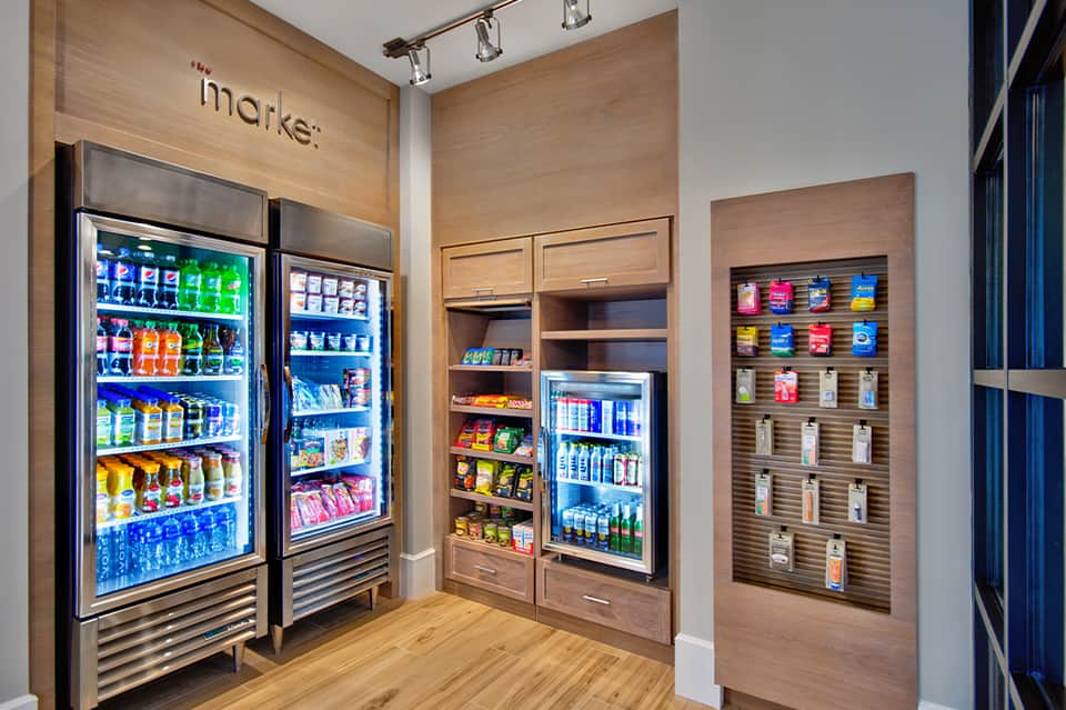 Hotel market with refrigerated beverage coolers, snack shelves, and wooden interior design