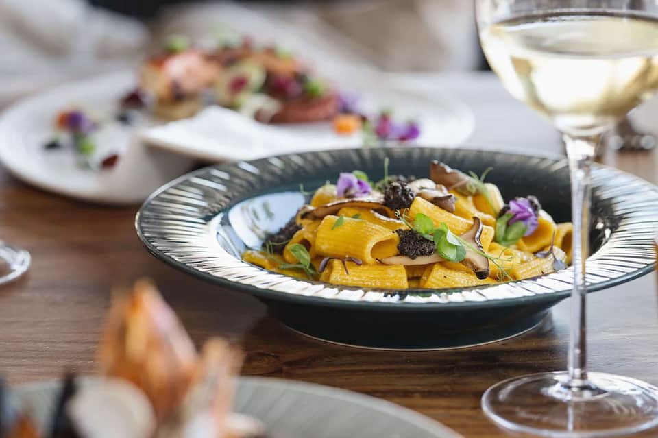 Elegant plated cuisine with caviar, microgreens, and floral garnish paired with white wine