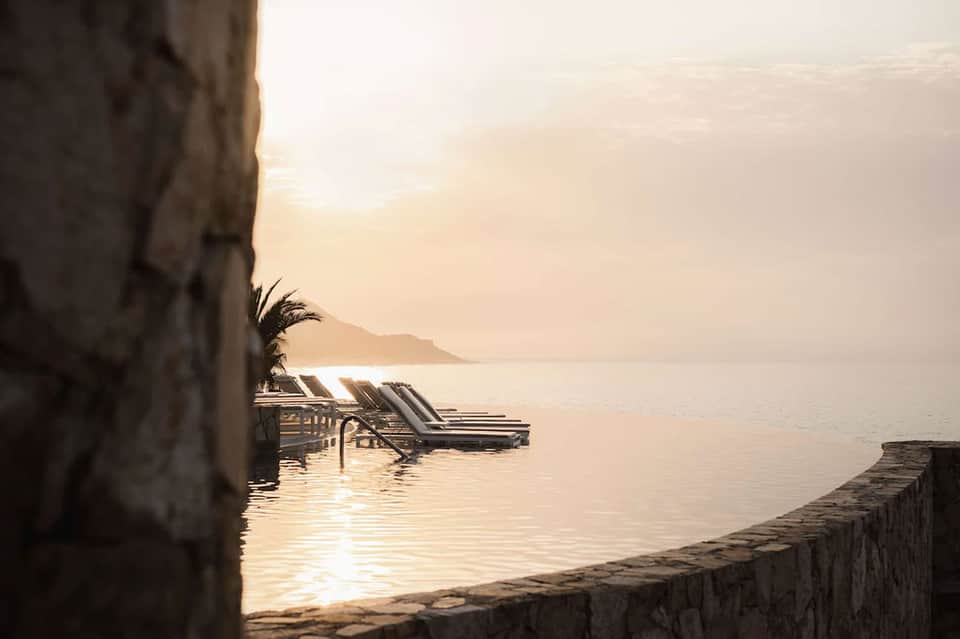 Serene waterfront deck with lounge chairs, calm sea, and golden hour sunrise lighting