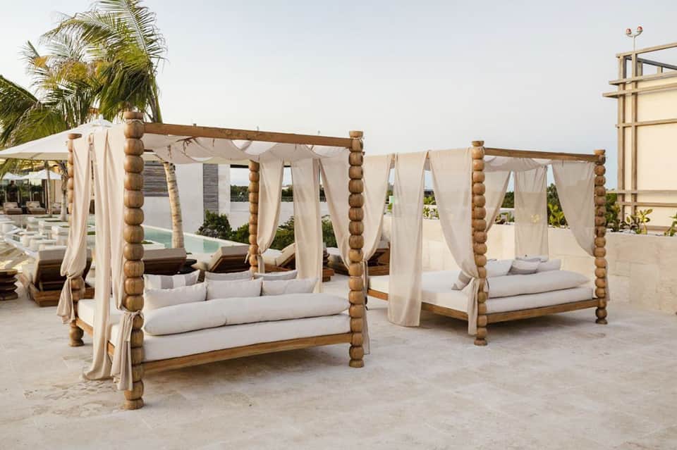 Luxury beach resort cabanas with cream drapes and wooden posts by pool