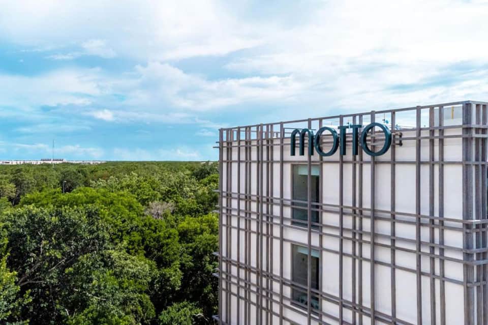 Modern hotel building exterior with grid pattern facade overlooking lush tropical forest canopy