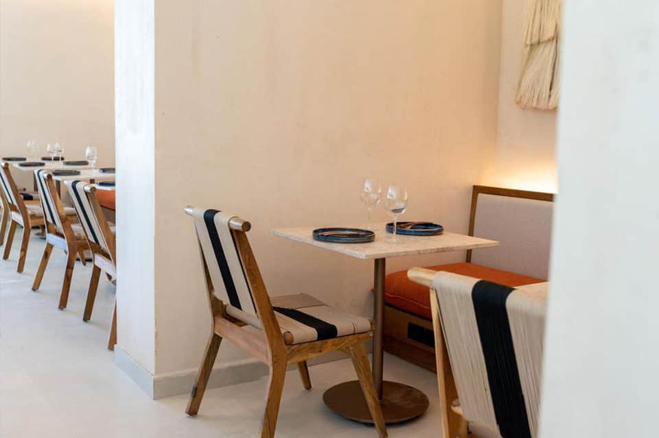 Intimate restaurant booth with wood chairs, small table, and warm ambient lighting