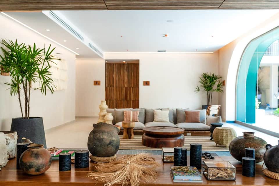 Luxury resort lounge with neutral furnishings, decorative vessels, plants, and turquoise door