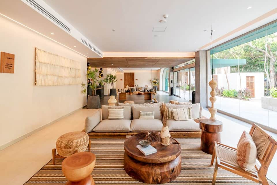 Upscale resort lobby with beige sofa, wooden accents, and ocean view through glass doors