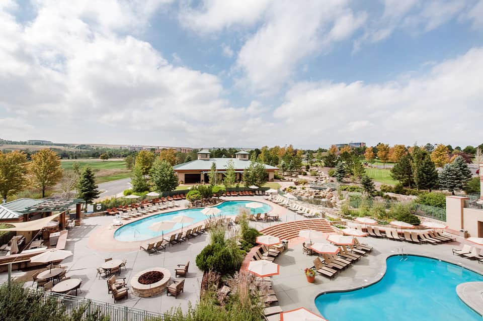 Aerial view of expansive resort with multiple pools, loungers, landscaping, and rural countryside surroundings