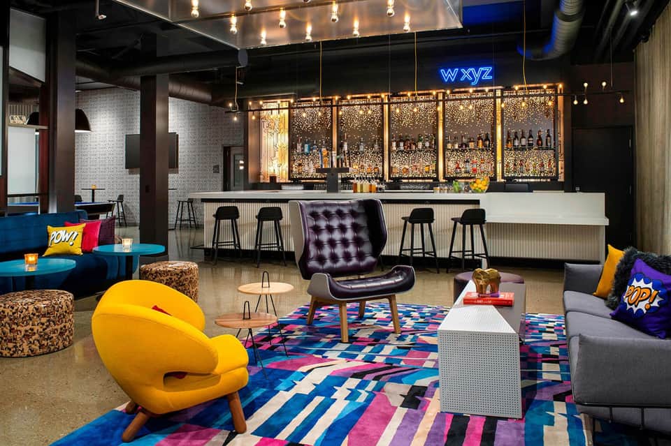 Modern hotel lounge with colorful seating, bar, and contemporary design elements