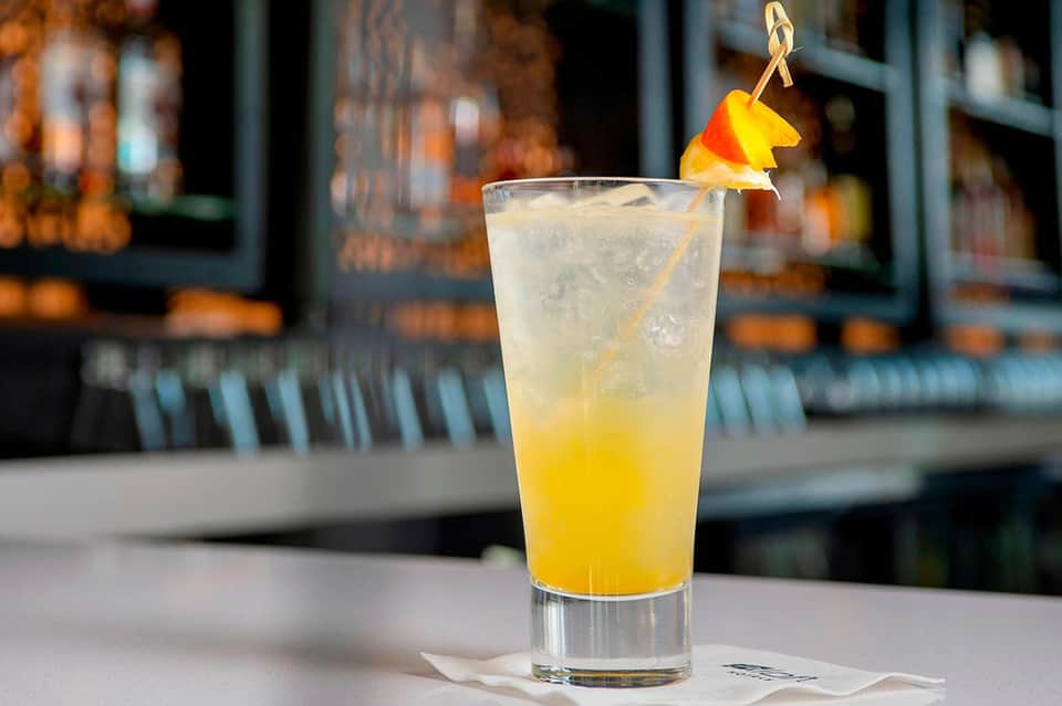 Refreshing citrus cocktail with orange peel garnish served at beachside bar