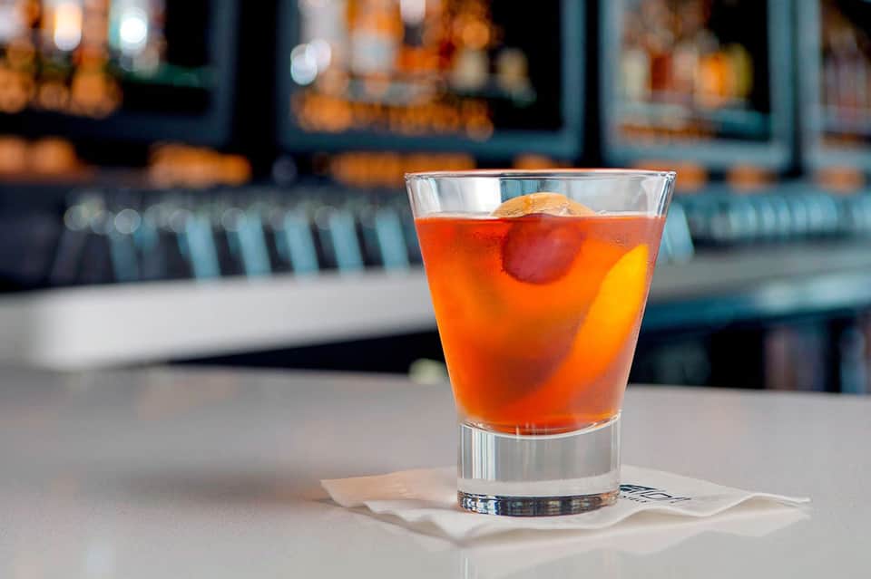 Colorful cocktail with ice and cherry at upscale bar counter