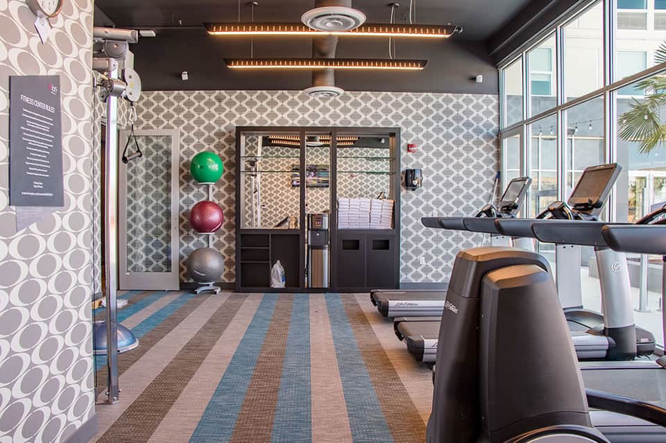 Modern fitness center with exercise equipment, patterned wallpaper, and large windows