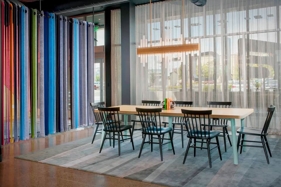 Modern hotel meeting space with colorful fabric panels, wooden table, and glass walls