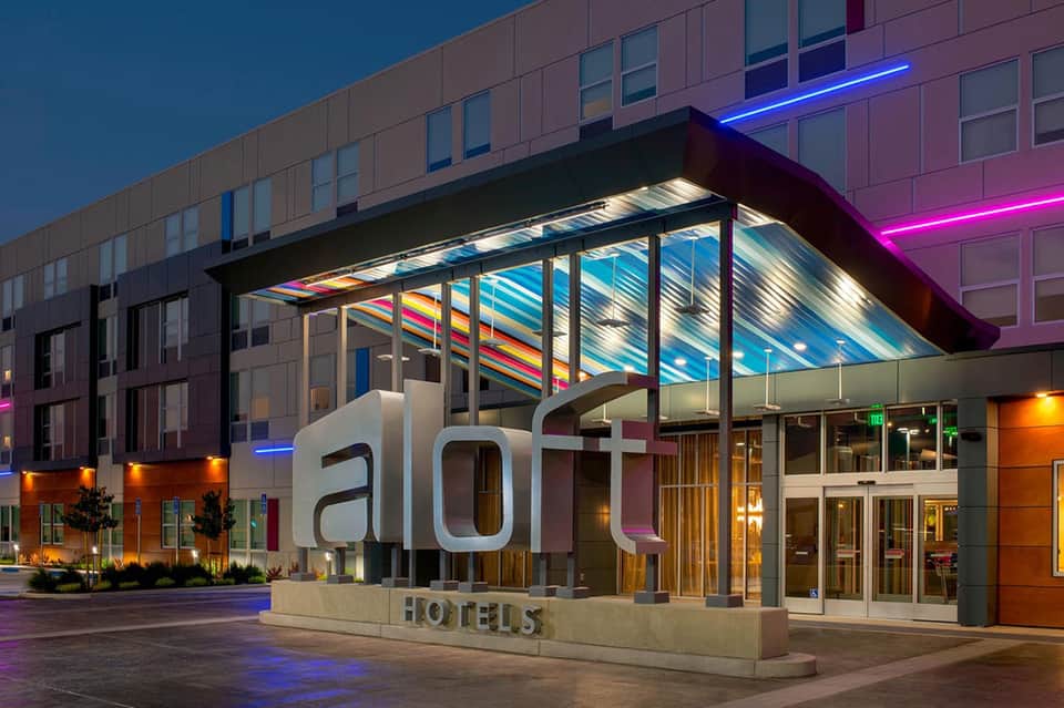Aloft Hotels modern entrance at dusk with colorful skylight canopy and neon accent lighting