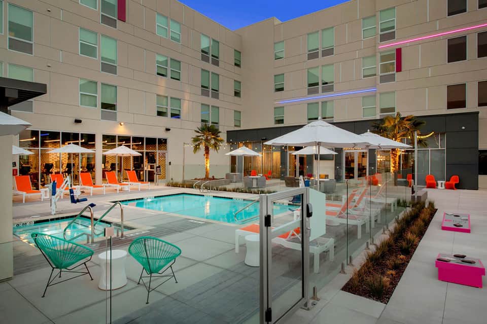 Modern resort pool deck with bright turquoise water, umbrellas, and contemporary building architecture