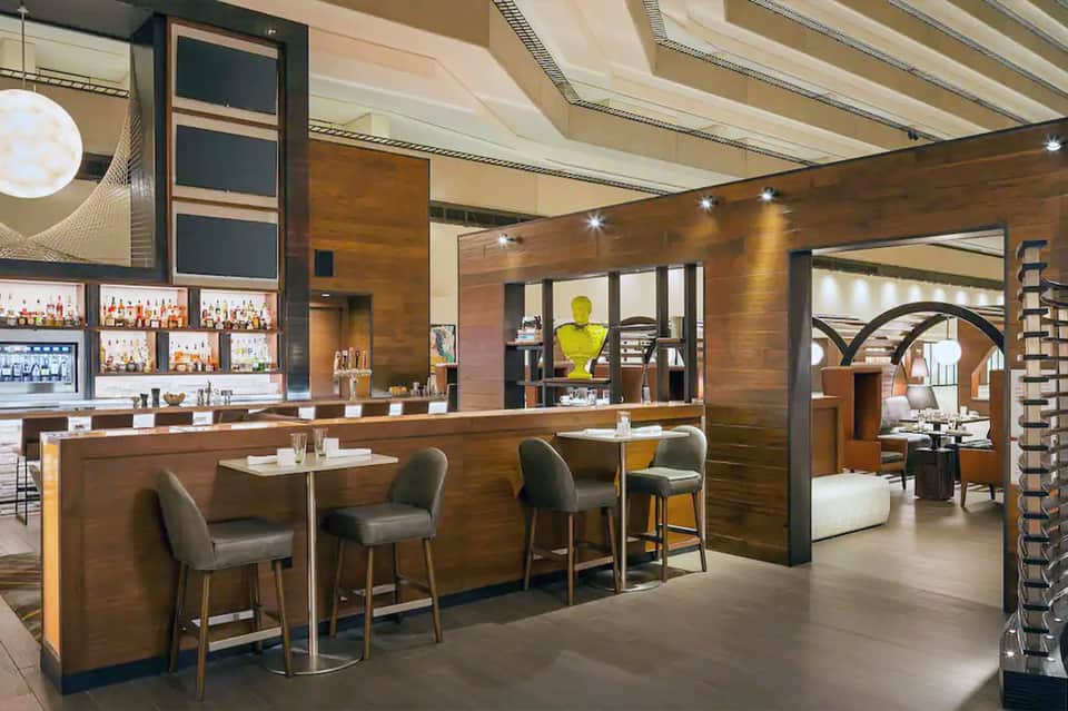 Contemporary hotel bar and lounge with wood paneling, retractable ceiling, and open floor plan