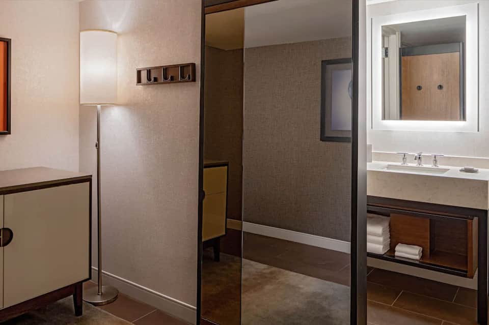 Modern hotel bathroom with marble sink, walk-in shower, and taupe finishes