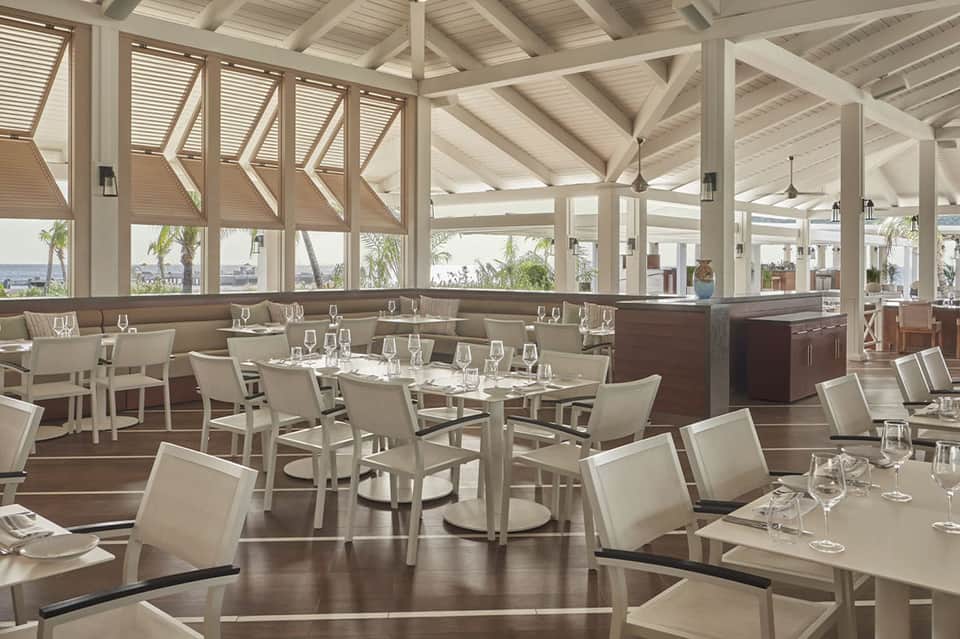 Upscale dining room with white ceiling beams, brown booths, and panoramic windows