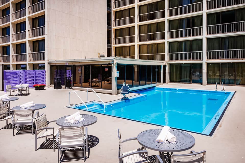 Resort outdoor pool with bright blue water, lounge chairs, and multi-story hotel building backdrop