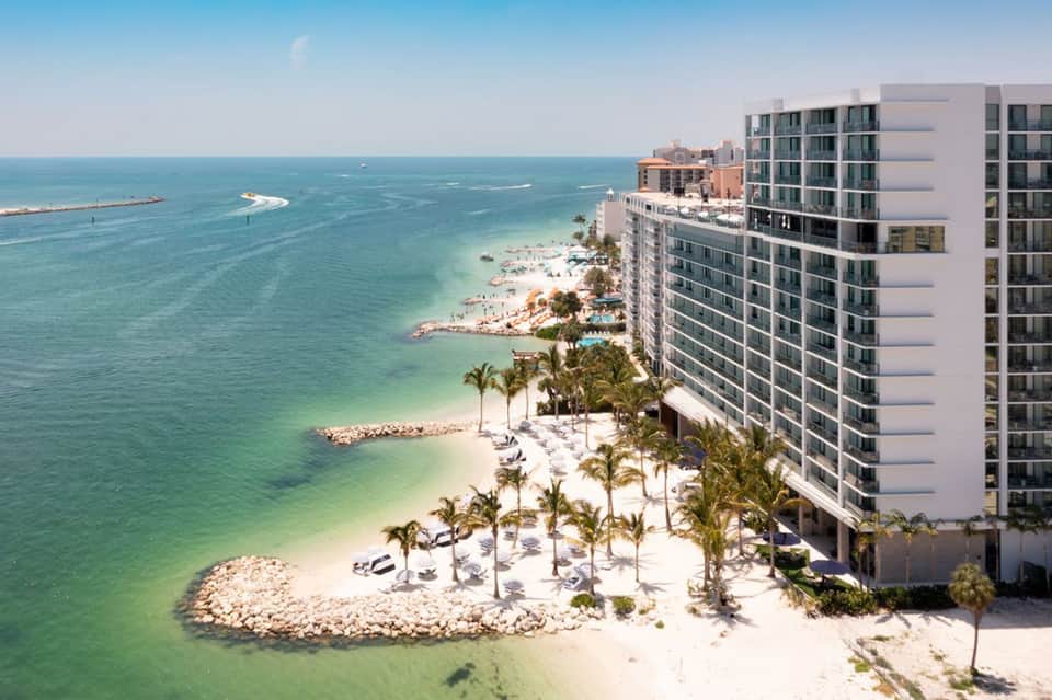 Beachfront high-rise hotel with private beach, palm trees, and turquoise water