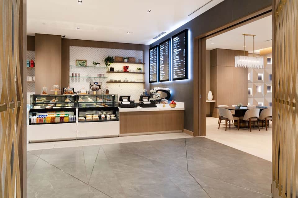 Modern hotel café with display cases, menu boards, wood accents, and seating area
