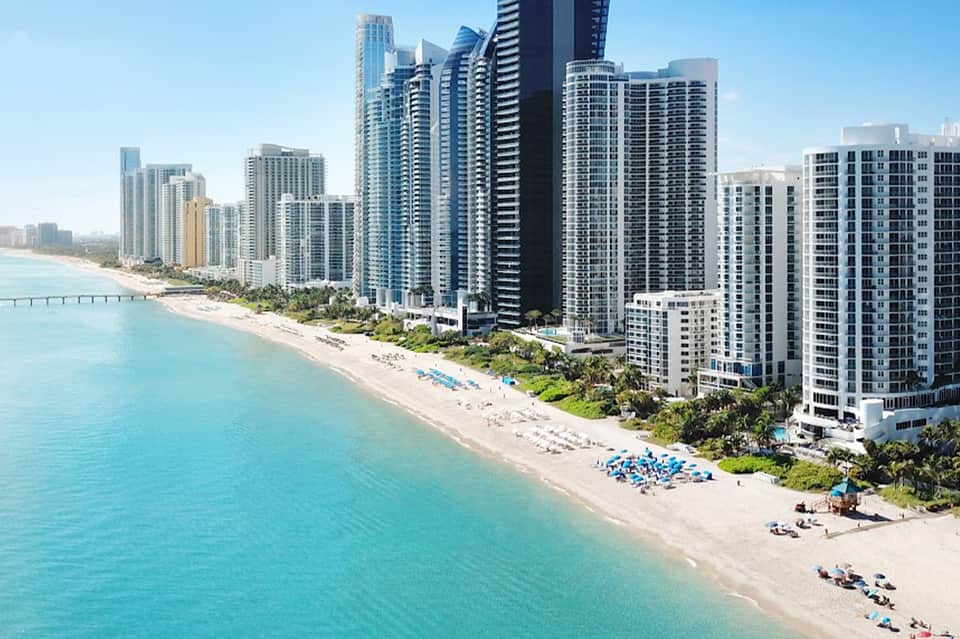 Aerial view of beachfront high-rise hotels and turquoise ocean with sandy beach