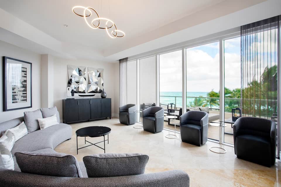 Luxury beachfront condo living room with modern furniture, panoramic ocean views, and floor-to-ceiling windows