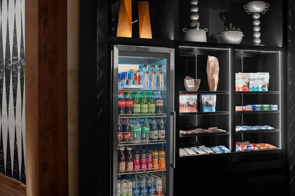 Modern beverage station with refrigerator, black shelving, and retail products