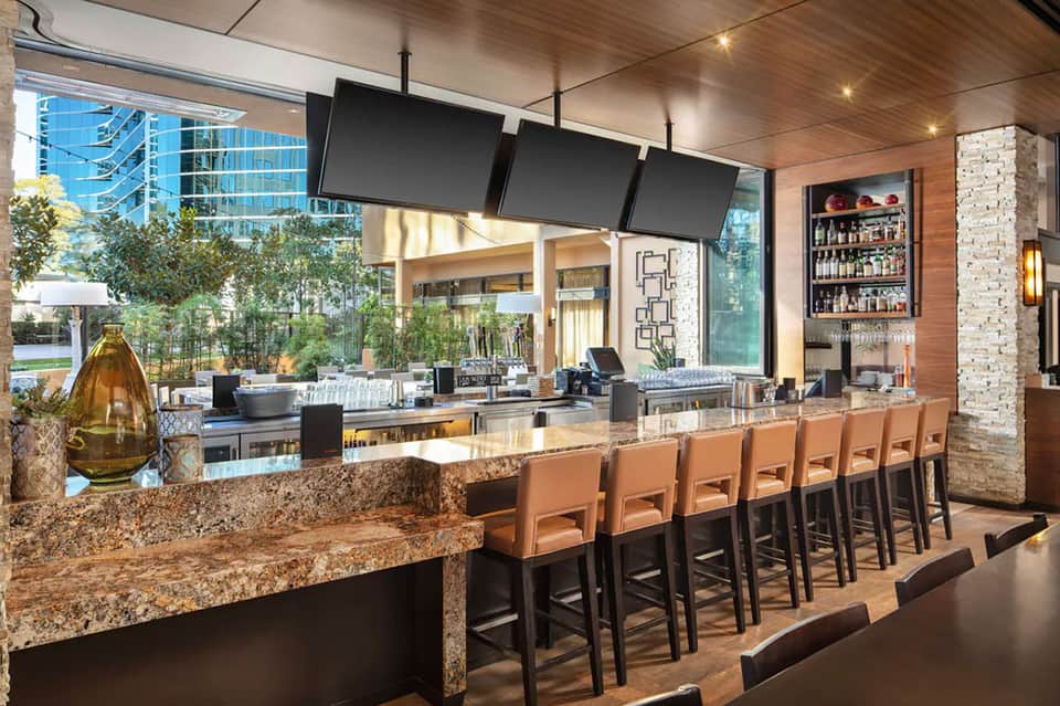Modern bar lounge with granite counters, leather seating, hanging televisions, and large windows