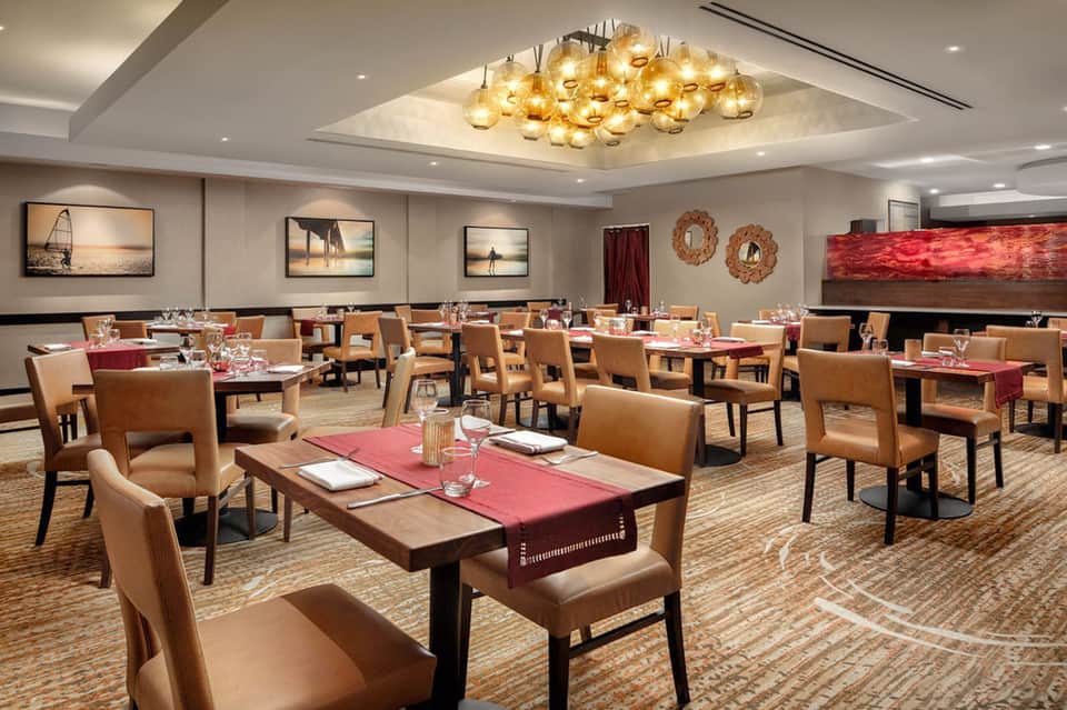 Elegant resort dining room with leather chairs, warm lighting, and ocean-themed wall art