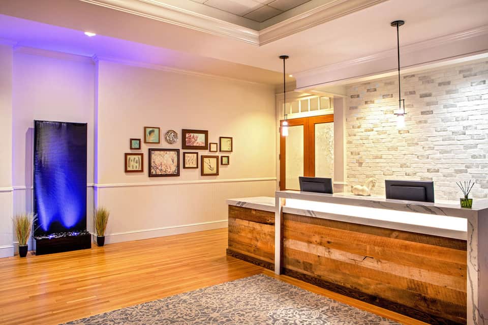 Elegant hotel lobby with modern reception desk, stone accent wall, and decorative water feature