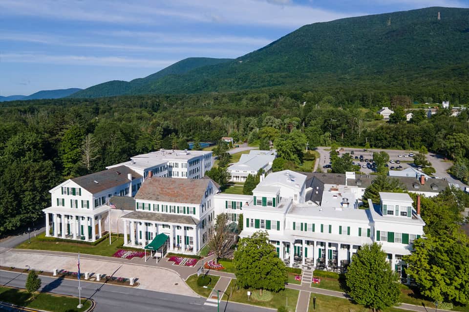 Upscale resort campus with colonial-style white buildings nestled in forested mountain setting