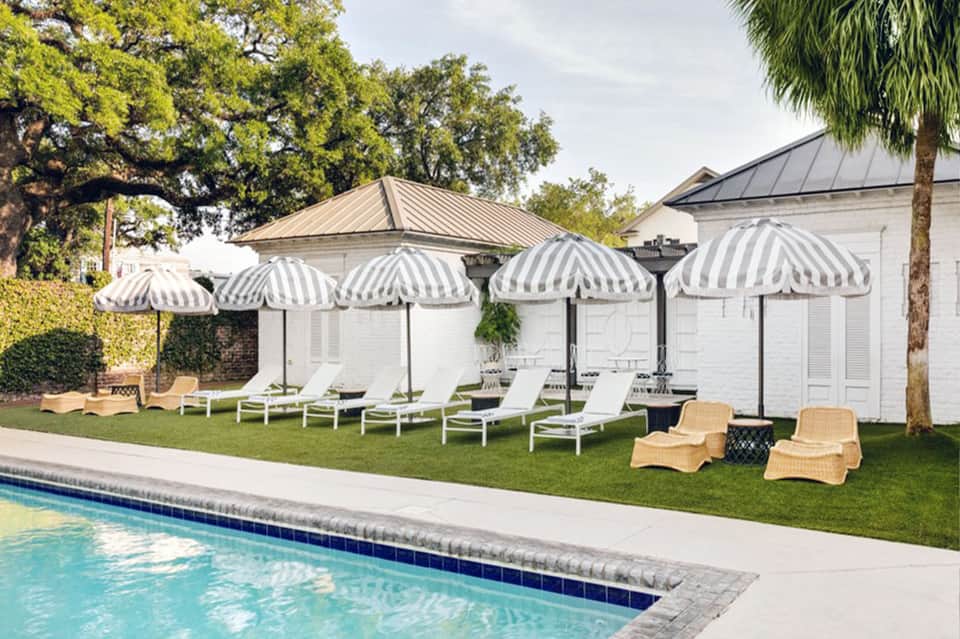 Poolside cabanas with striped umbrellas, lounge chairs, and manicured lawn area