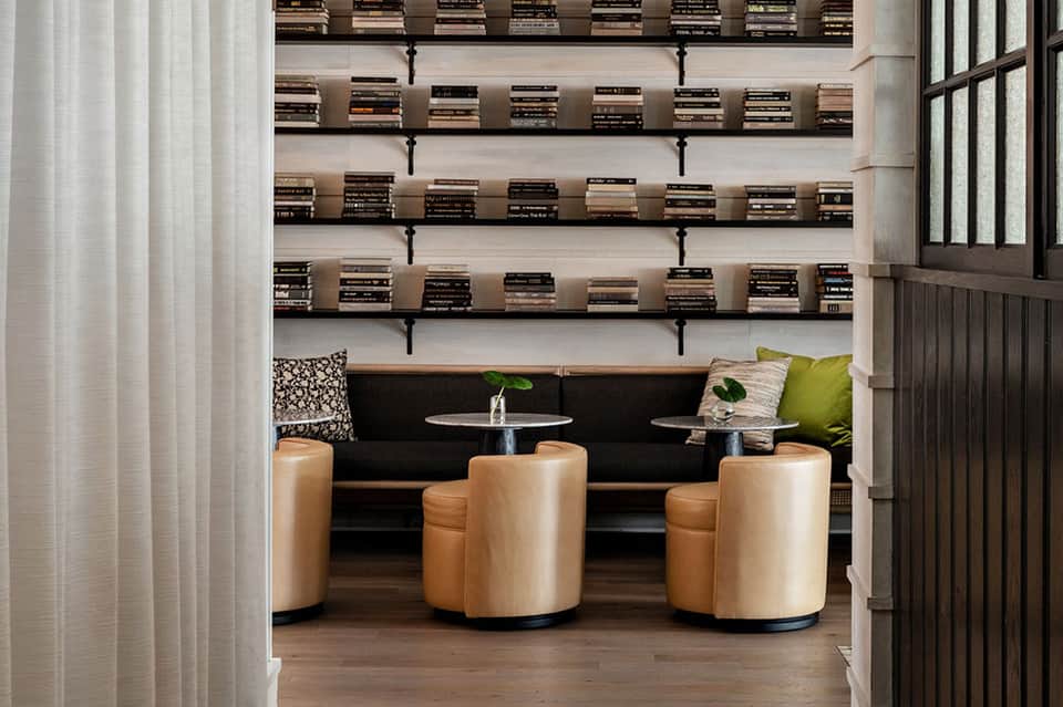 Luxury lounge interior with black sofa, tan barrel chairs, and floating bookshelves above