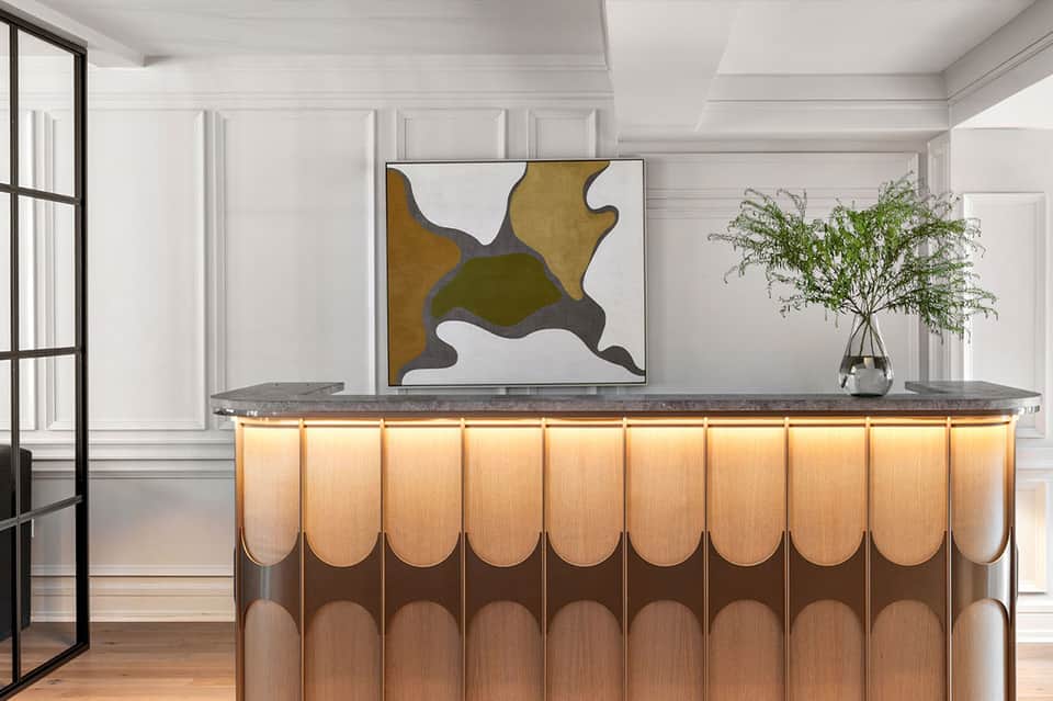 Modern hotel reception desk with geometric wood pattern and contemporary art on wall